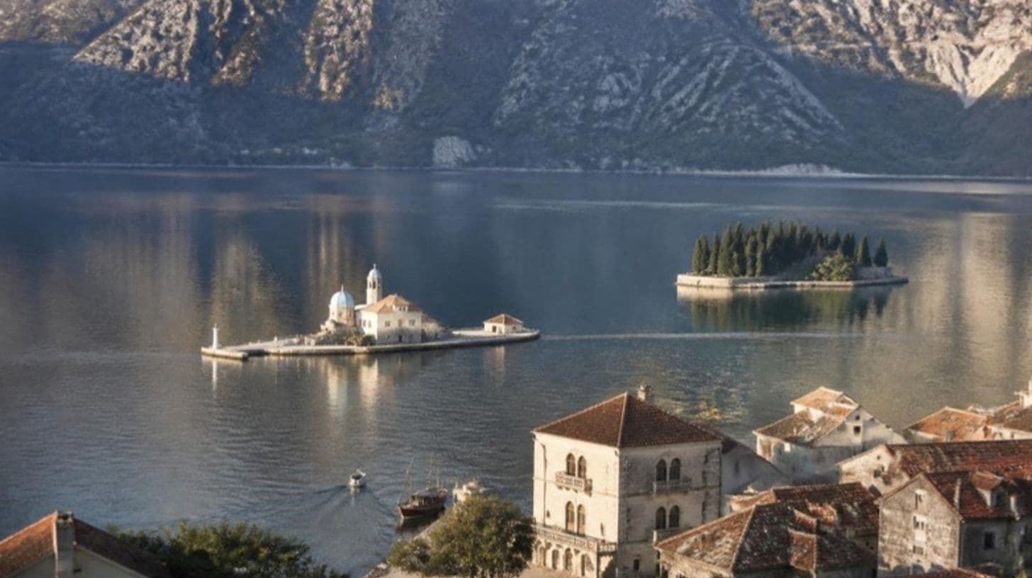 Eine Insel mit Kirche in der Bucht von Kotor vor einem kleinen steinernen Küstenort