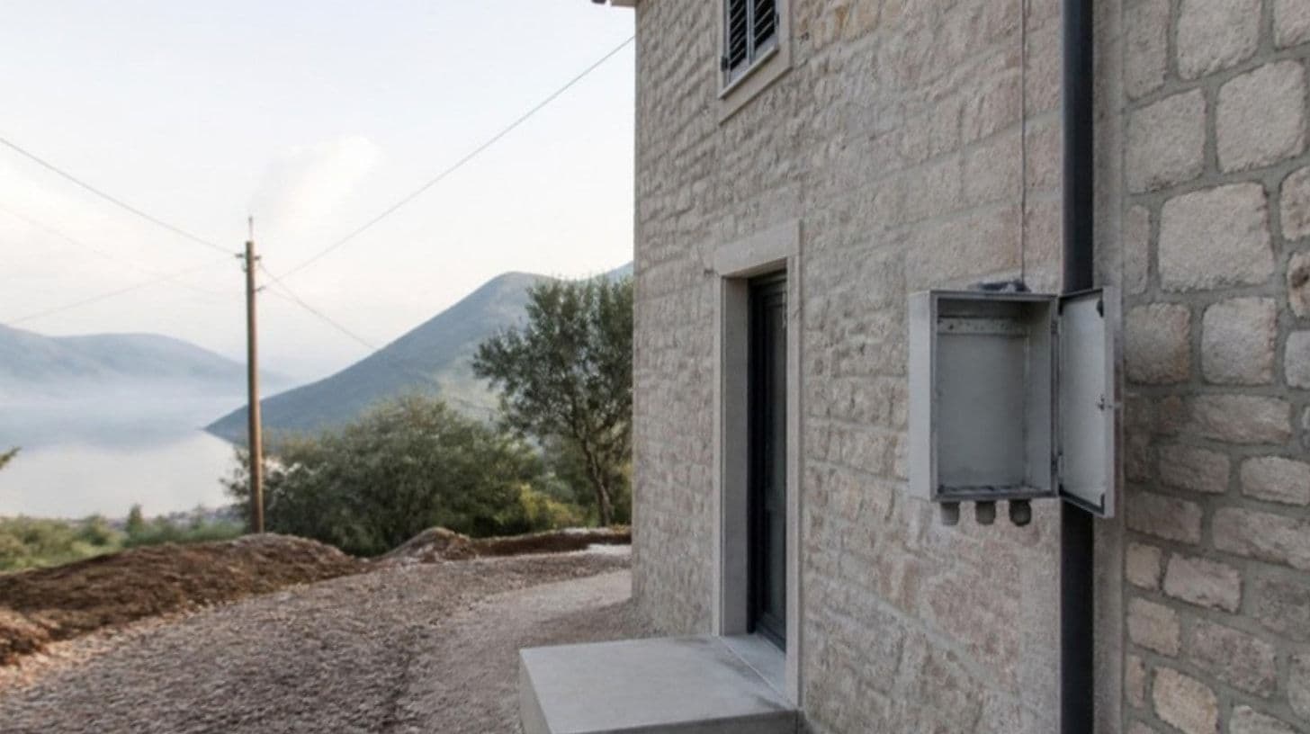 Casa nuova in pietra con armadietto del contatore vuoto sulla facciata e un palo della luce dietro