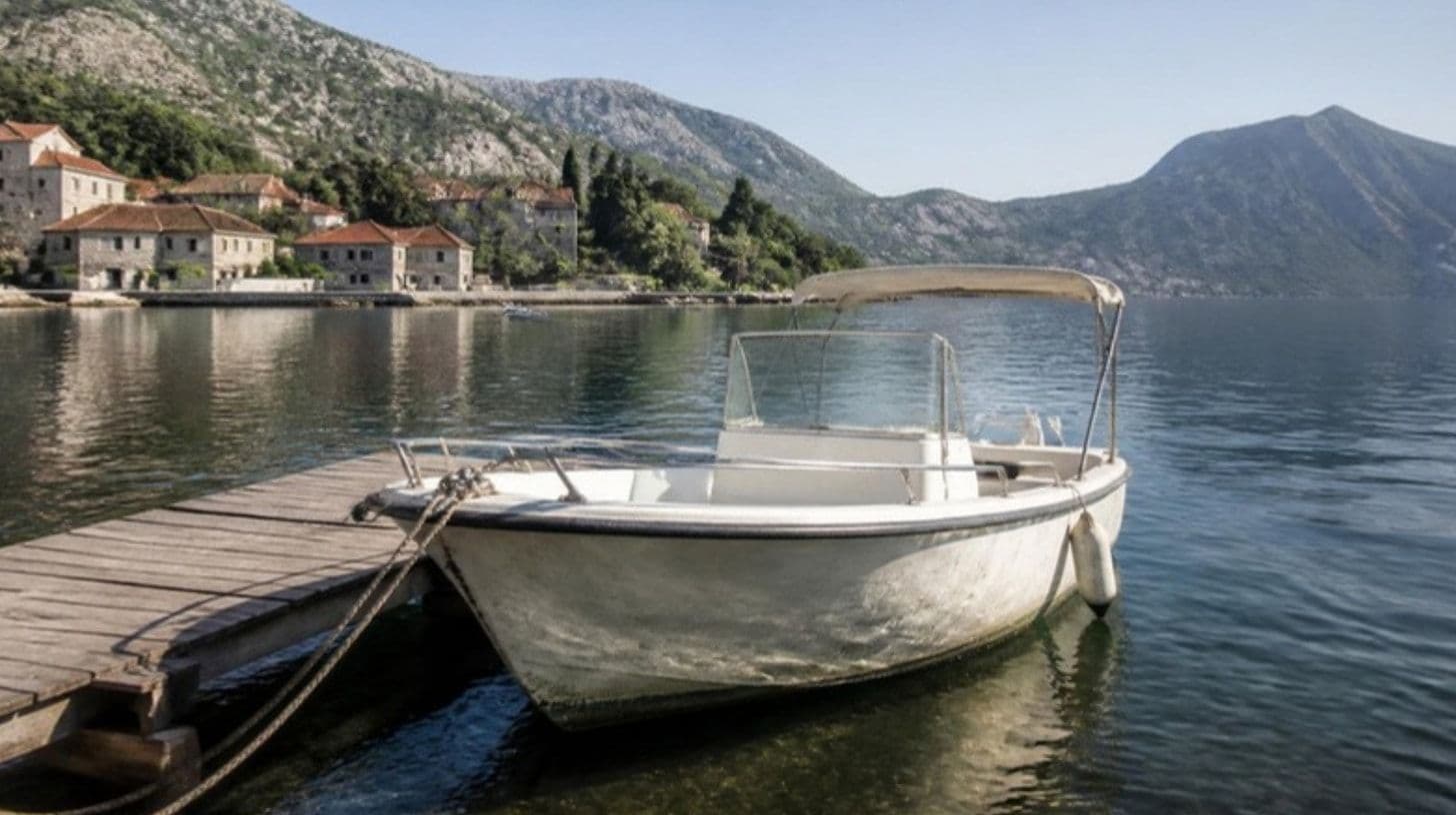 Gebrauchtes weißes Motorboot an einem Holzsteg in einer ruhigen Bucht