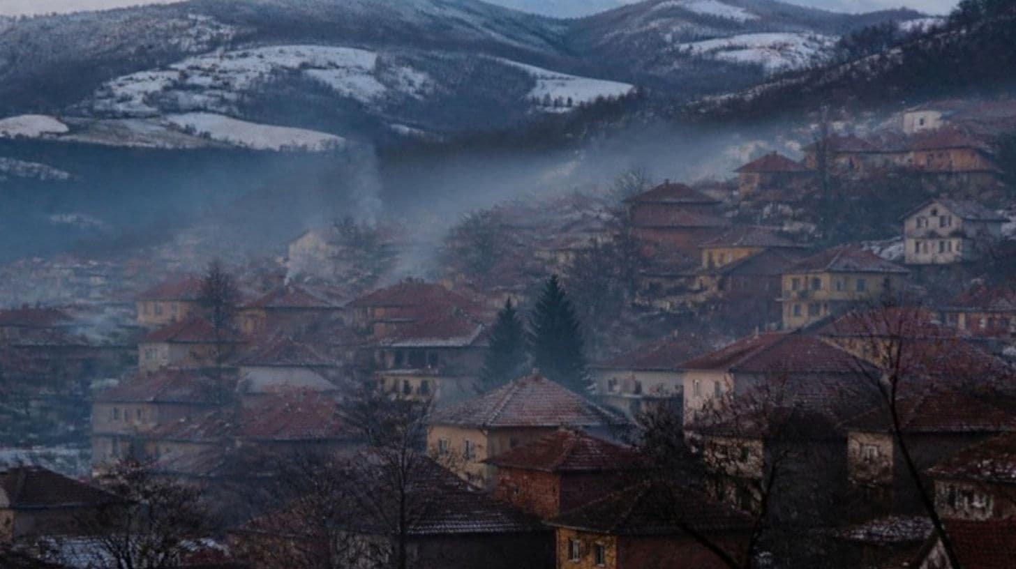Chimney smoke over town roofs on a winter evening