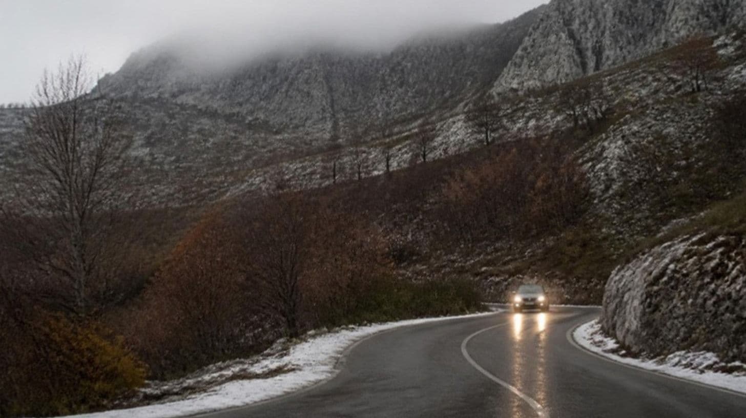 Ein Auto mit eingeschaltetem Licht in der Kurve einer Bergstraße