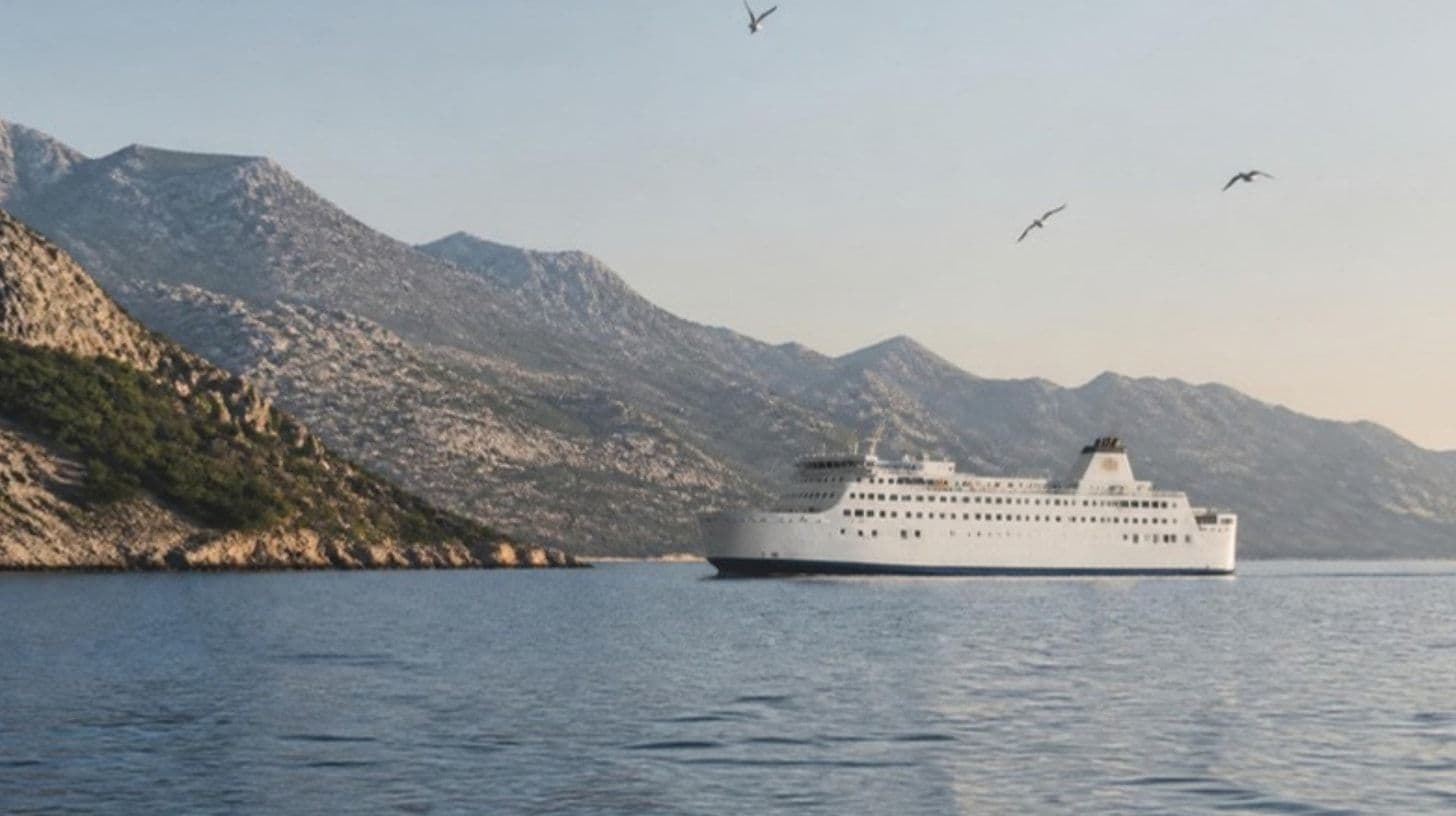 A large white ferry sailing on the calm Adriatic sea along a rocky coast